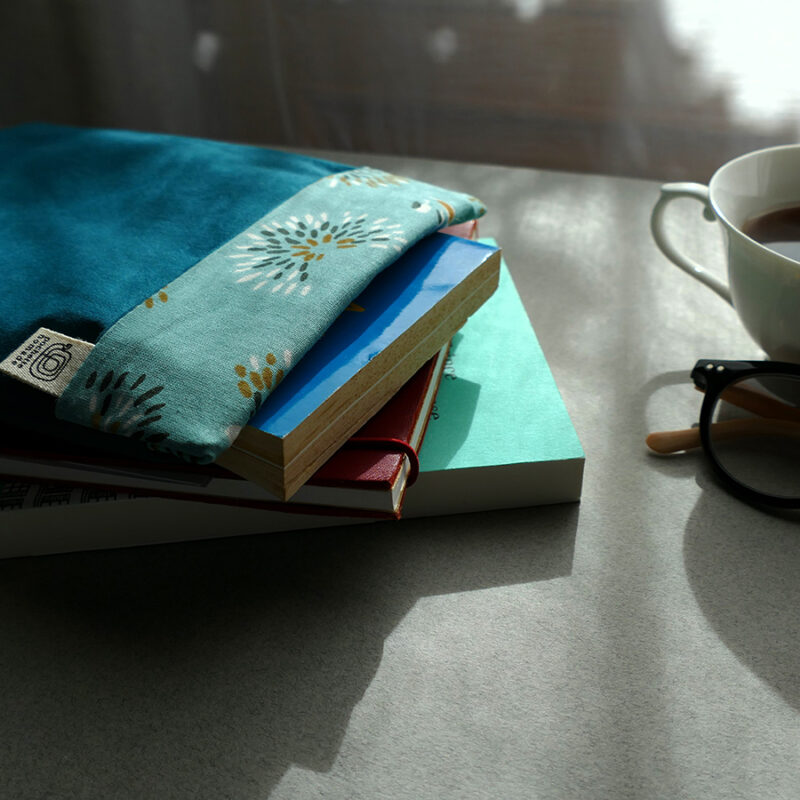 Pochette à livre Modestine couleur bleu Canard sur carnet et un livre posée sur un bureau